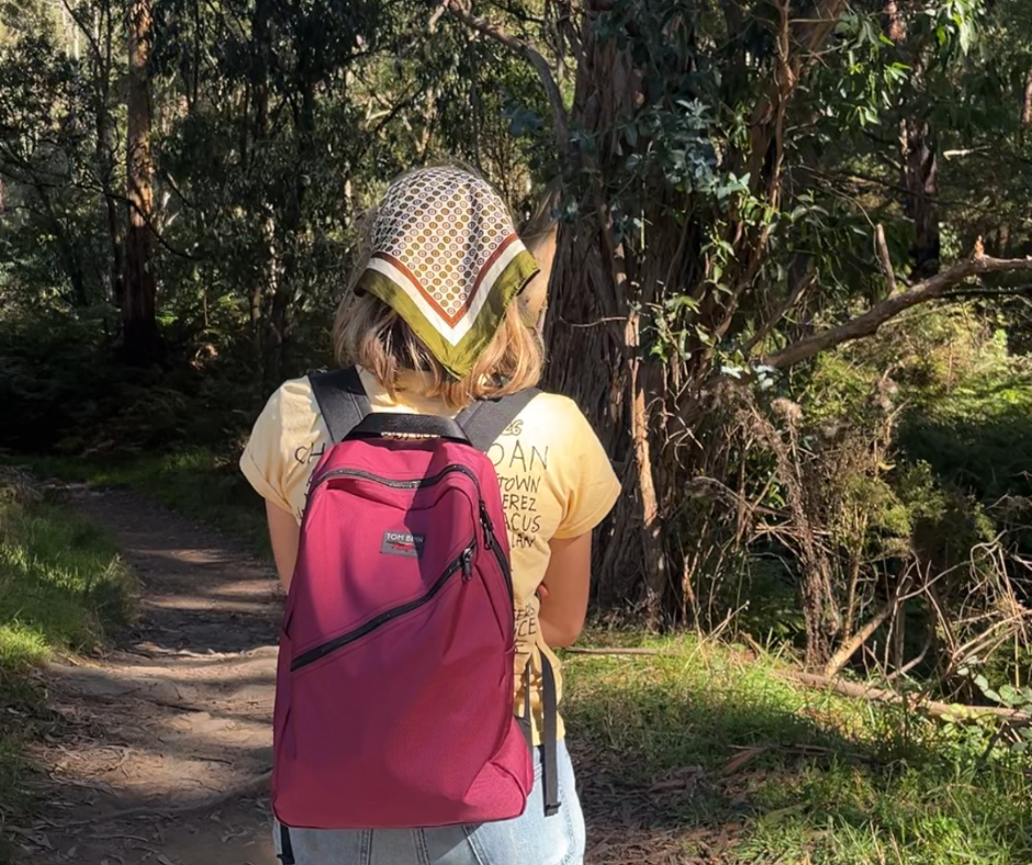 Person wearing a Daylight Backpack in Raspberry on wooded trail.
