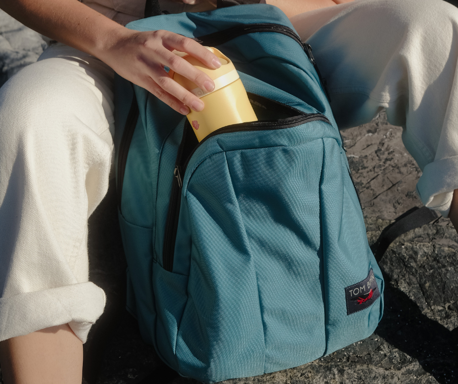 Person pulling a water bottle out of the exterior pocket of the Paramour in Agave