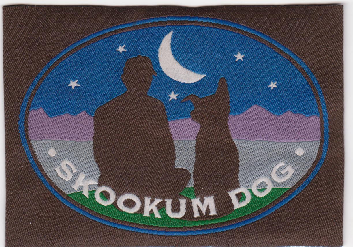 The Skookum Dog woven logo label shows a person sitting next to their dog with the moon and stars and mountains in the background.