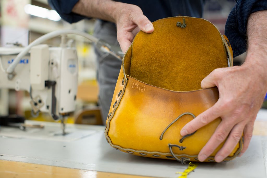 A person holding open a yellow leather handbag