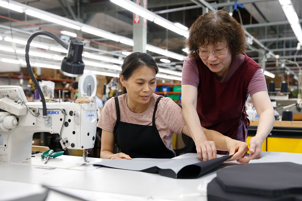 Lisa (Production Manager) working with Mei (Sewing Professional) on the production floor.