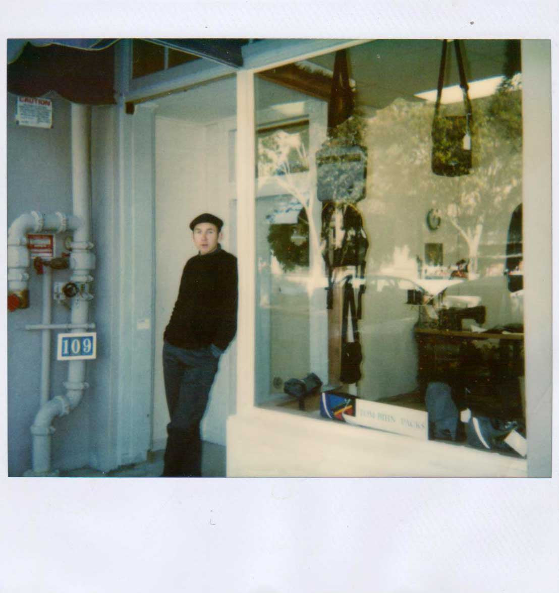 Tom stands leaning in the doorway of his first shop in Santa Cruz.