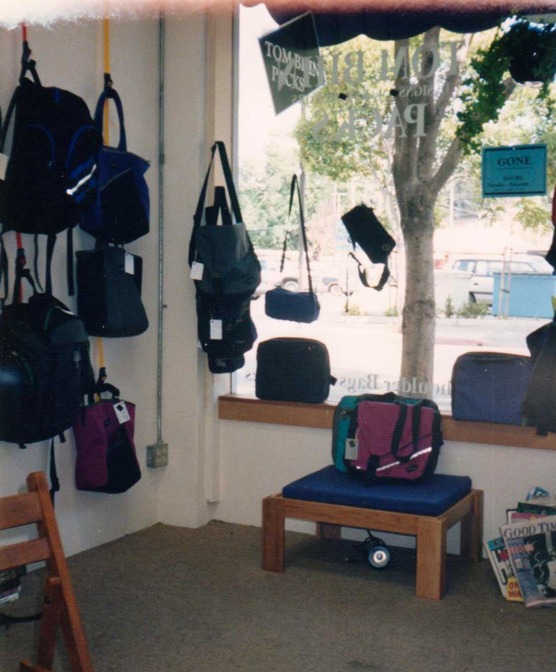 A photo showing the inside of Tom's Santa Cruz shop. There's vintage TOM BIHN designs on the walls, window sill, and benches!