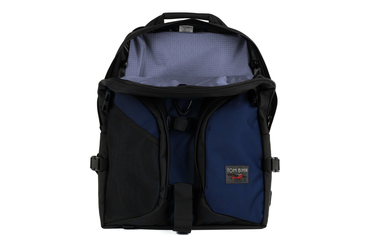 visible variant TB0114-DKDL^^The Brain Bag in Deep Blue (dark blue) 525 Ballistic with the front main compartment zipper opened to reveal its Dusk (purplish-blue with light purplish-blue grid) 210 Cerylon interior.