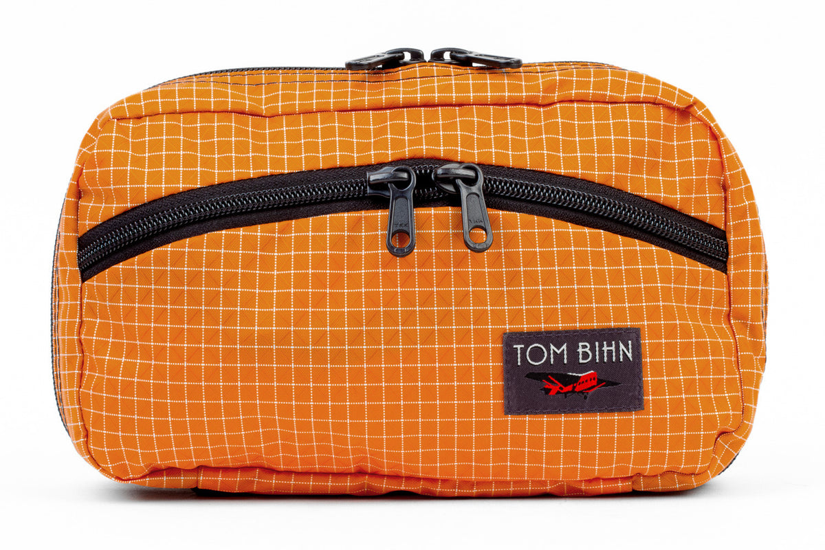 visible variant TB0419-ZD^^The front of a Handy Little Thing #2 in Zest (orange) 200 Halcyon showing the front zipper with two slider and logo at the bottom-right corner.