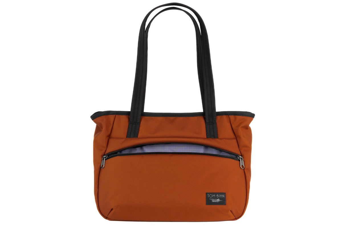 visible variant TB0715-TKDL^^Photo of the Nomad Tote in Burnt Orange Ballistic with Dusk (purplish-blue with dark bluish-purple grid) 210 Cerylon interior.