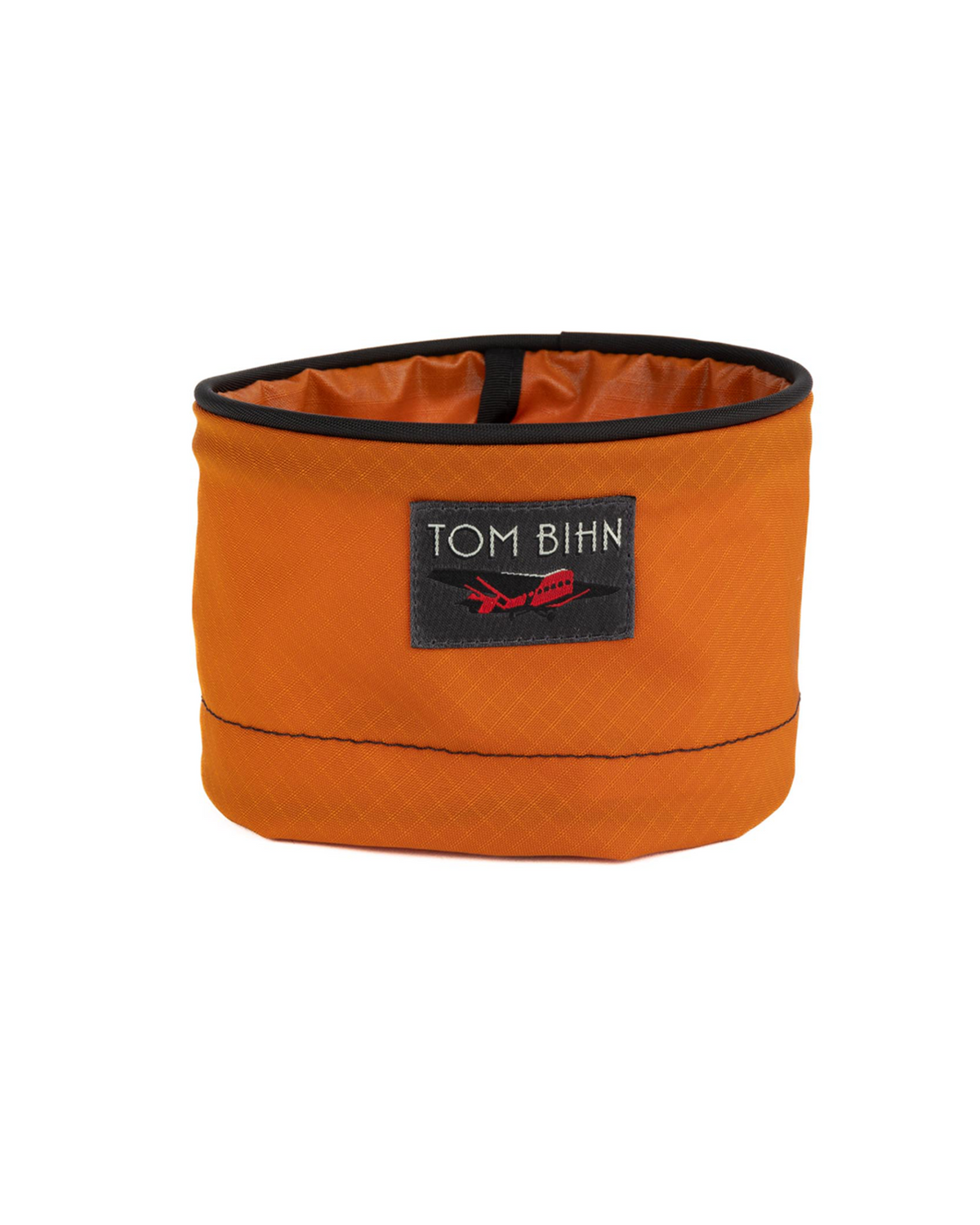 Orange travel bowl with black rim and 'Tom Bihn' logo on a white background