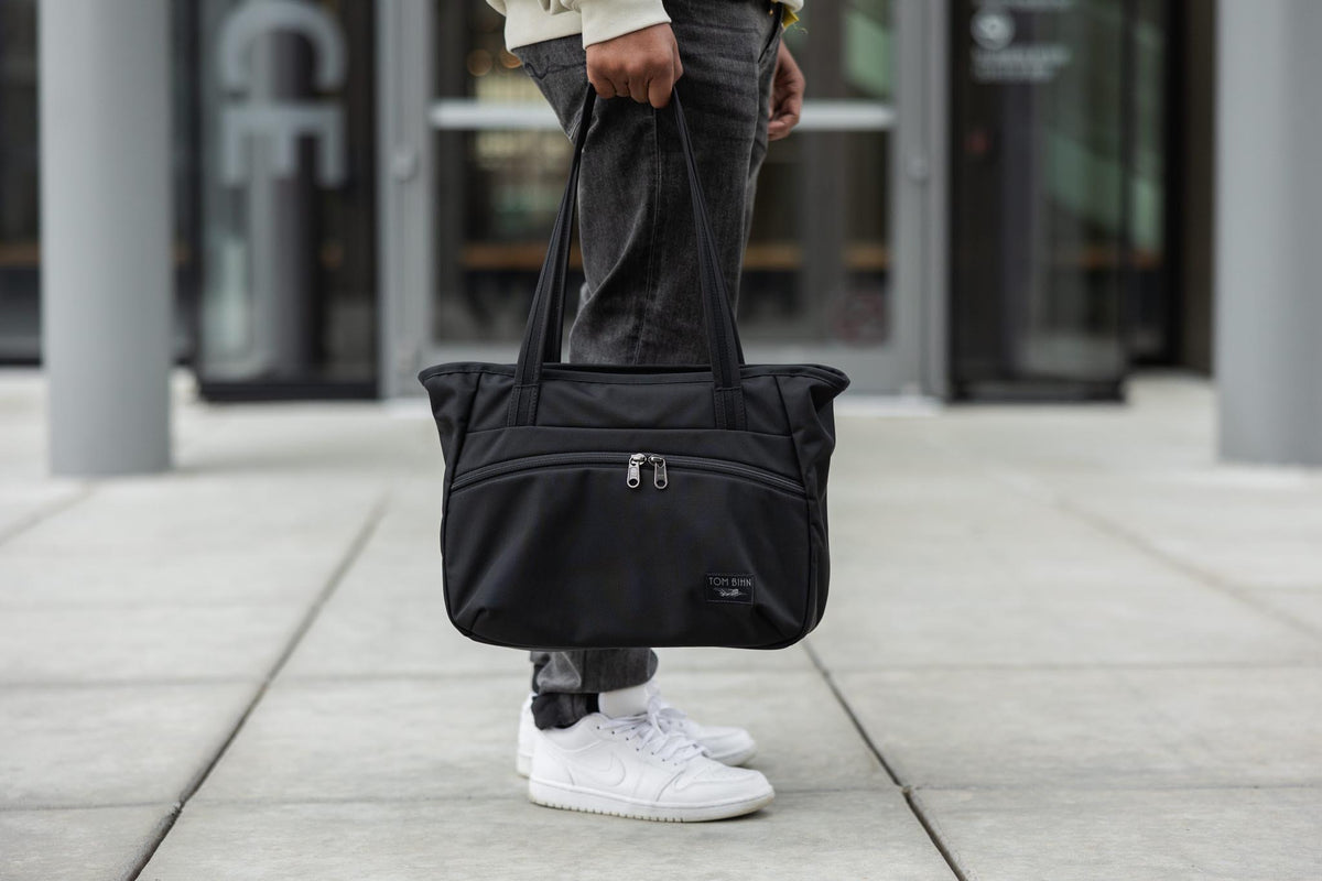 visible lifestyle^^A person holding a Nomad Tote by the handles.