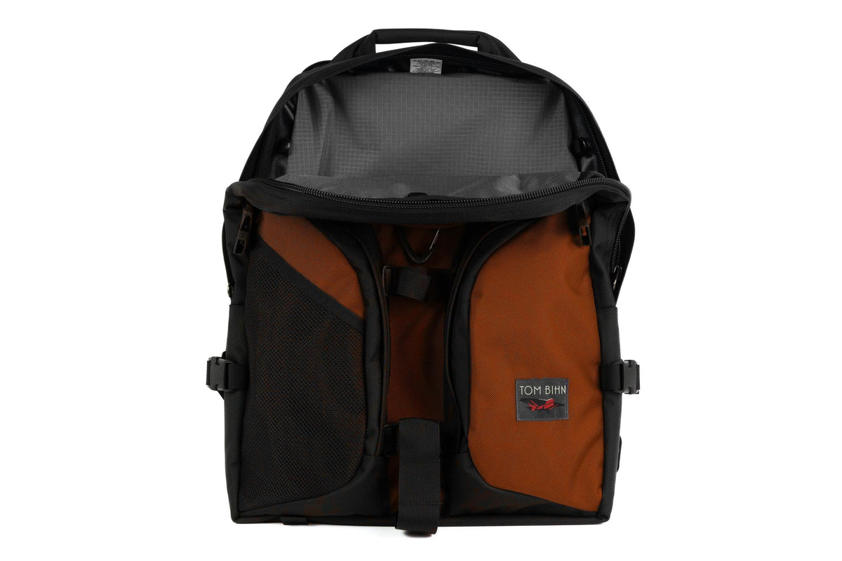 visible variant TB0114-TKGL^^The Brain Bag in Burnt Orange Ballistic with the front main compartment zipper opened to reveal its Mountain Grey (grey with light grey grid) 210 Cerylon interior.