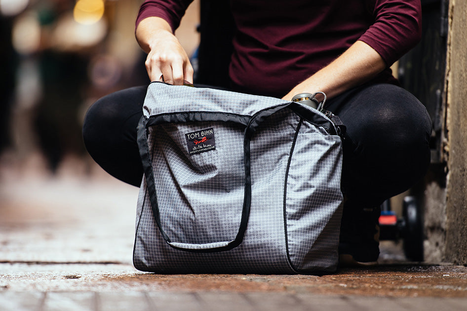 visible lifestyle^^A person crouching and using a Large Zip-Top Shop Bag