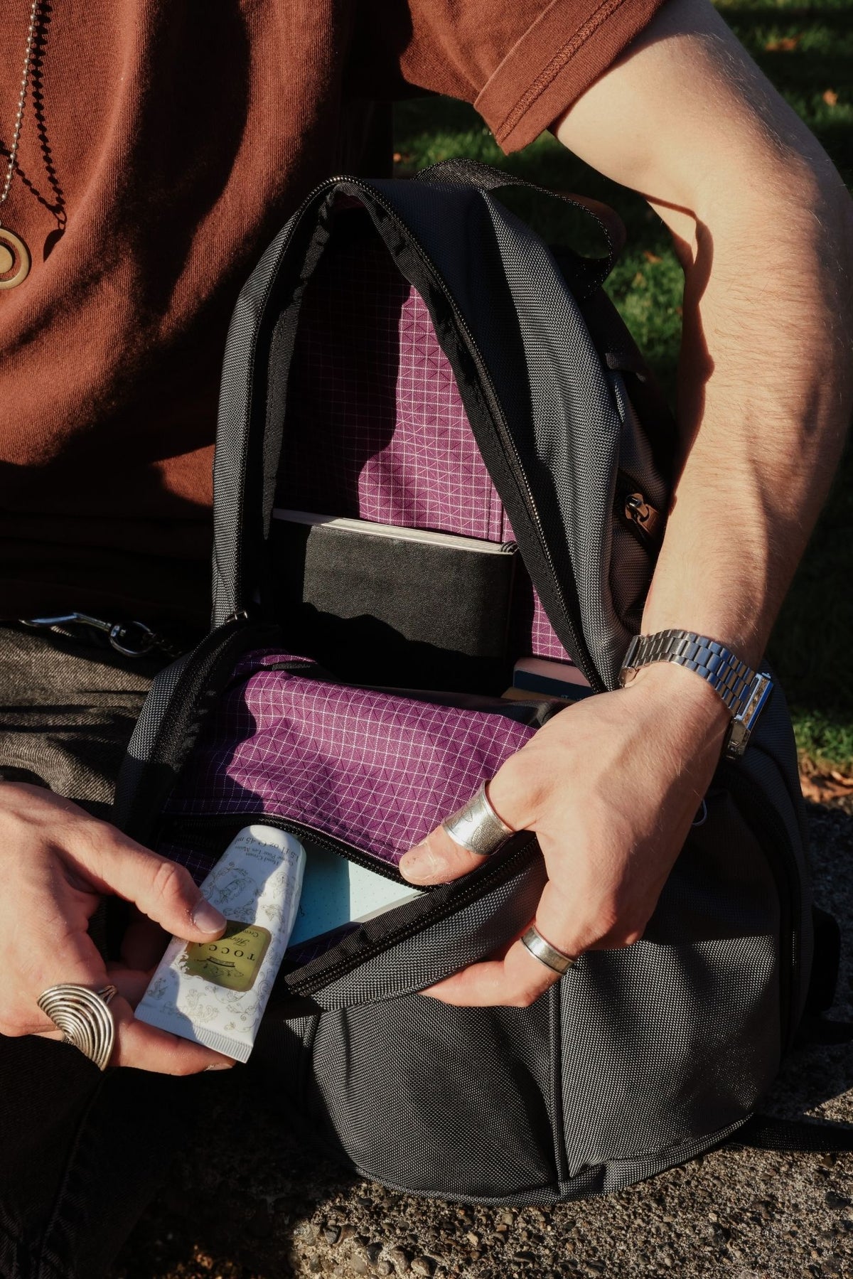 visible lifestyle^^ Person putting lotion in top inner pocket of Luminary.