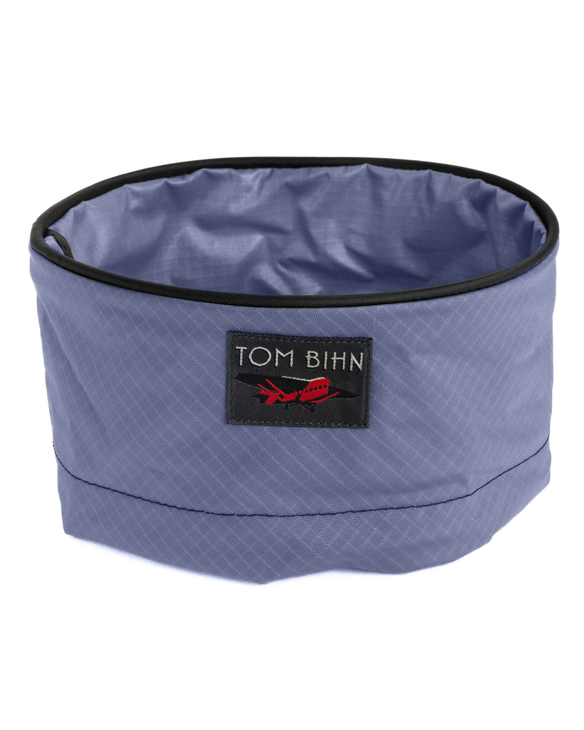 Blue pet bowl with black rim and Tom Bihn logo on a white background