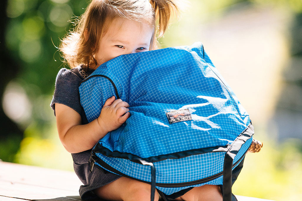 visible lifestyle^^A child holding a Large Zip-Top Shop Bag upside-down.