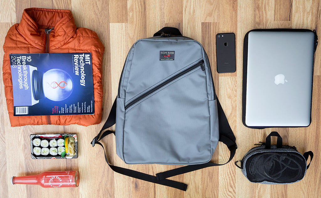 Possible loadout for the Daylight Backpack; a puff jacket, magazine, sushi lunch, bottle of soda, laptop and Cache, Small Snake Charmer with charge cables, and a phone.