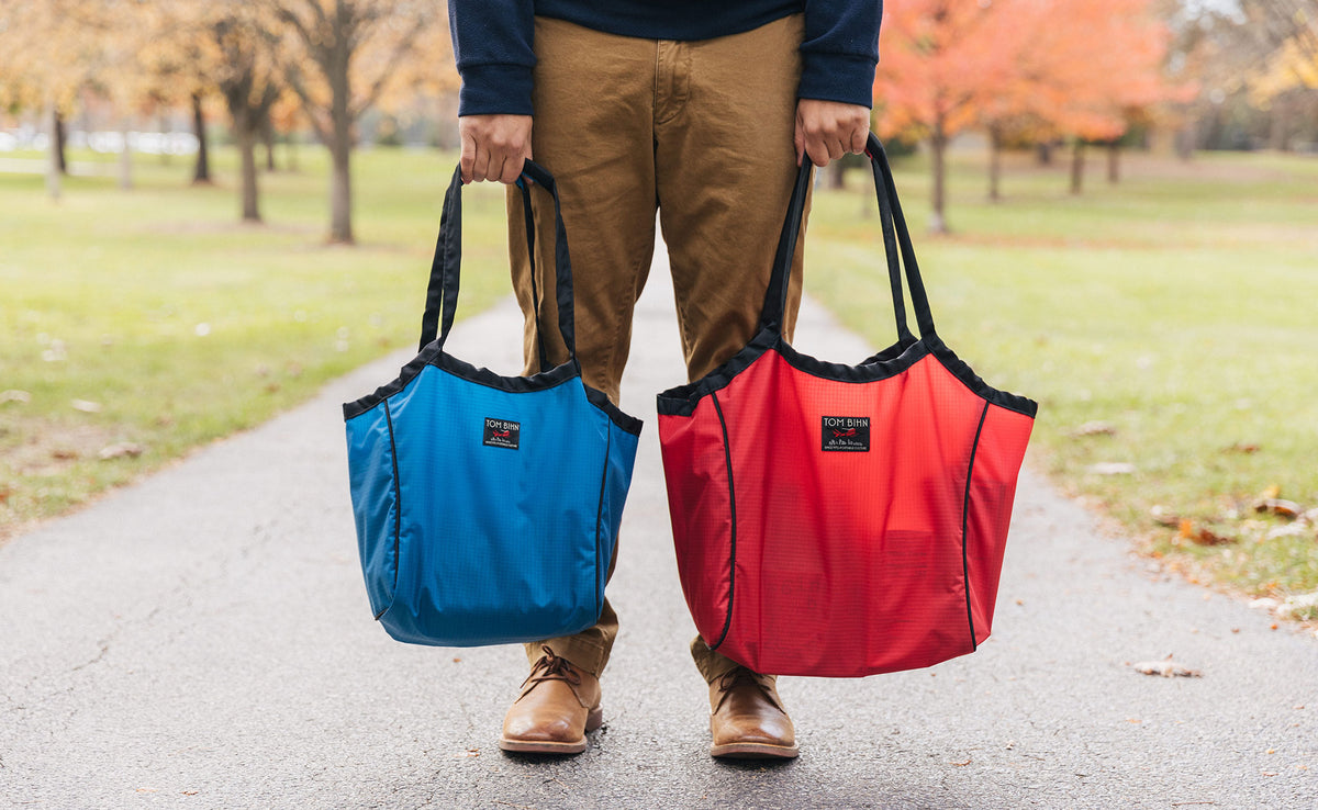 lifestyle visible^^Person holding Cobalt (Small) and Sangria (Large) Original Shop Bags side-by-side.