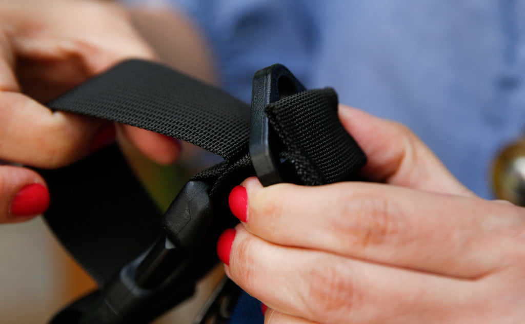 A person attaching the Stroller/Wheelchair Strap to the snaphook d-ring.