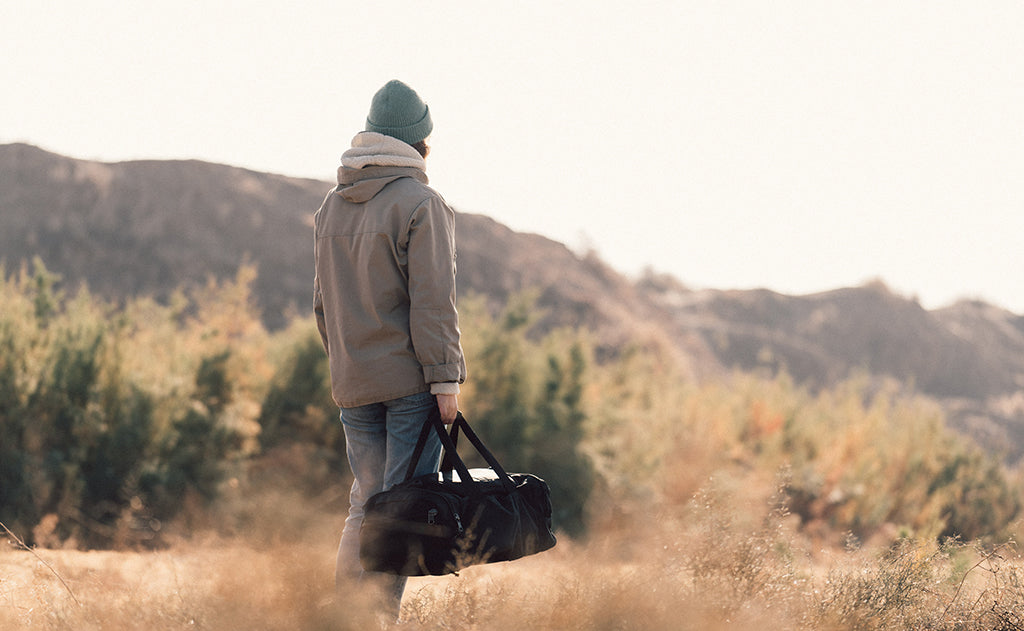 lifestyle visible^^A person carrying the Road Buddy Duffel via the padded carry handle.