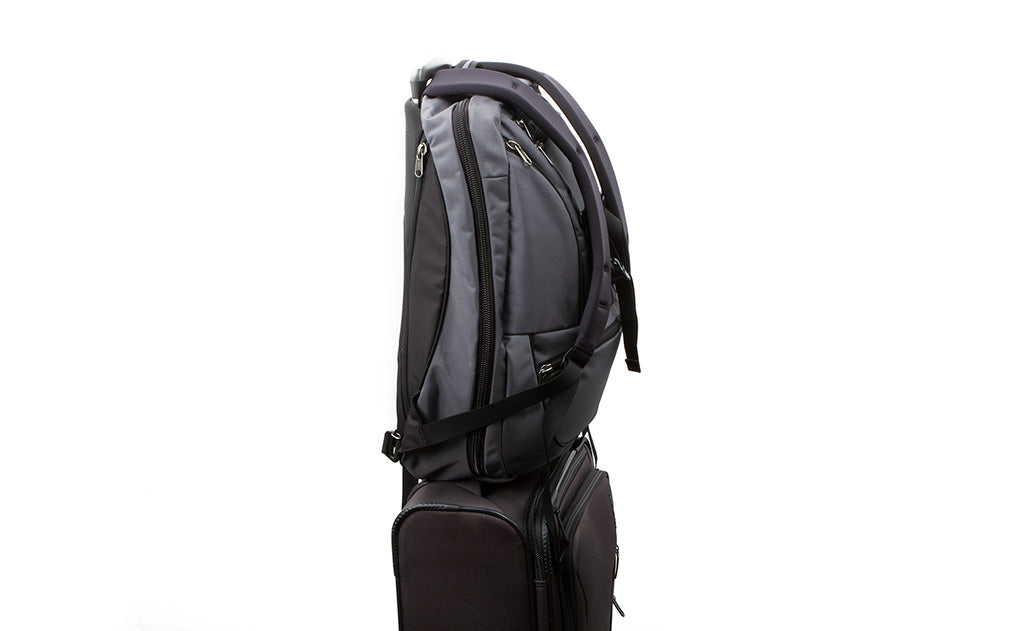 A profile shot of the Synik 30 slid on the handle of a roll-aboard piece of luggage, held in place by the handle slip through.