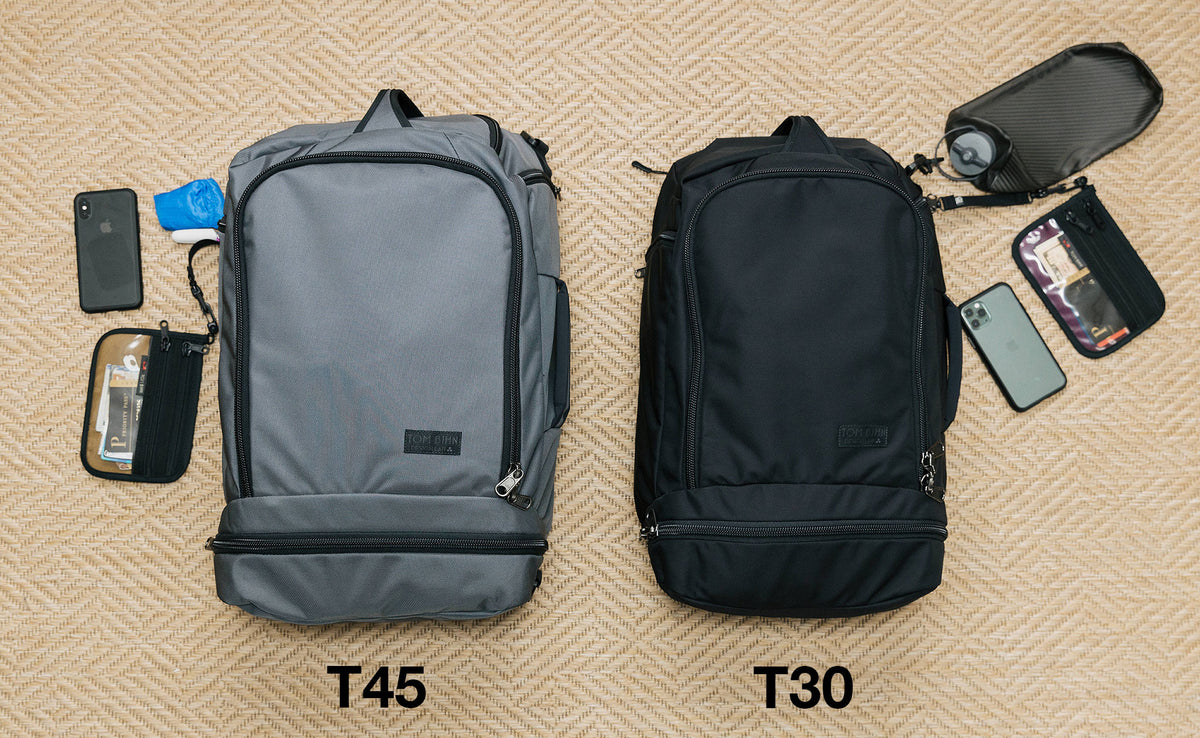 vA comparison of the fronts of the Techonaut 45 (left) and Techonaut 30 (right). The Techonaut 45 has a phone, Double Organizer Pouch and folded Pocket Travel Pillow next to it, and the Techonaut 30 has phone, Double Organizer Pouch and collapsible water bottle near 