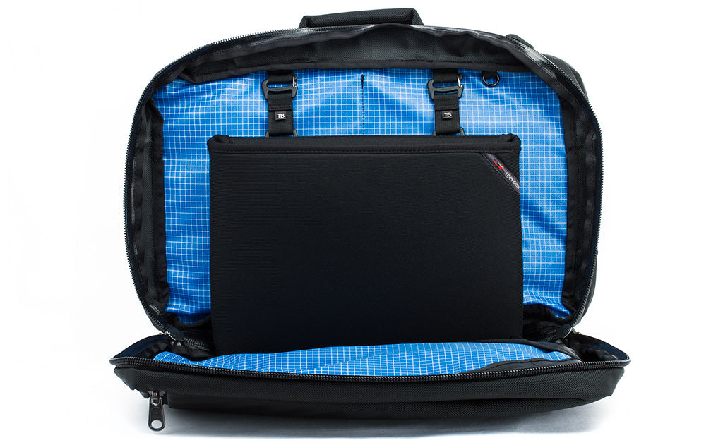 The rear main pocket of a Black 525 Ballistic exterior Western Flyer opened to reveal an Island (blue) 200 Halcyon interior with a Cache connected to the nylon loops sewn into the interior seam.