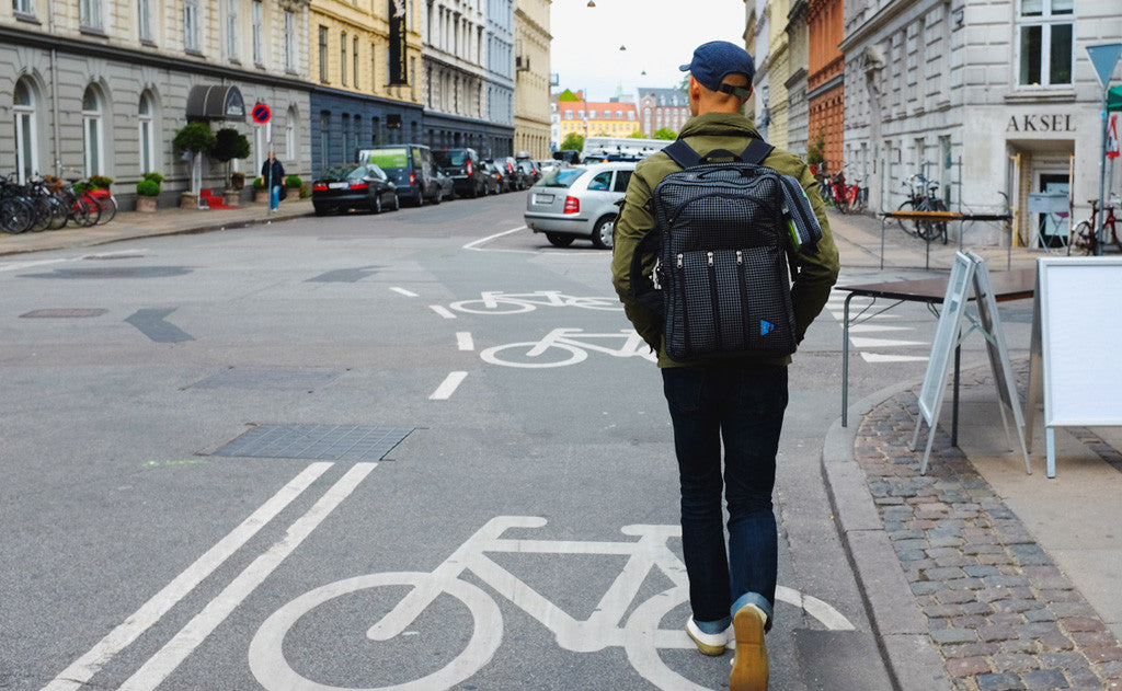 person walking down a street wearing a Tri-Star via the included backpack straps.