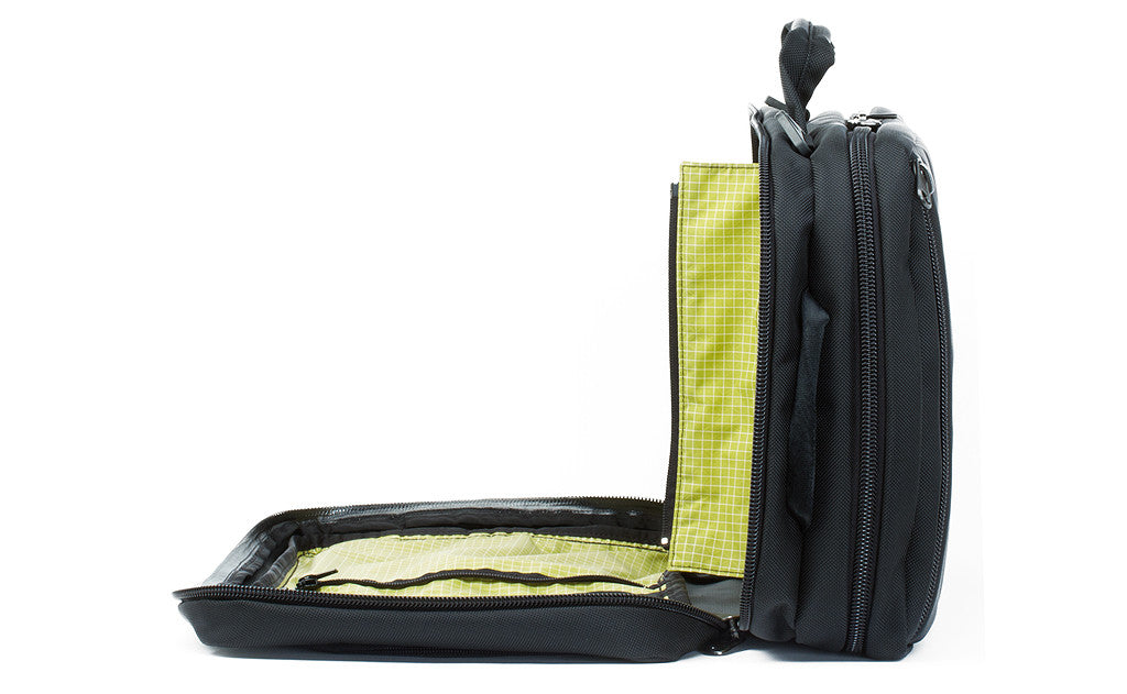 A profile shot of the front pocket of a Black 525 Ballistic exterior open showing the Wasabi (green) 200 Halcyon interior's zippered divider unzipped.