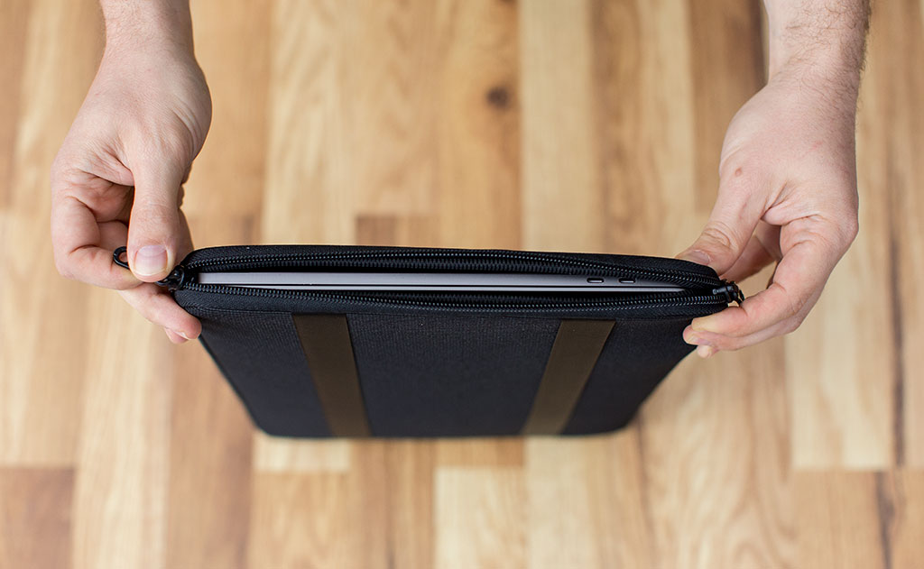 detail visible^^A laptop in a Cache being opened on the vertical zipper side.