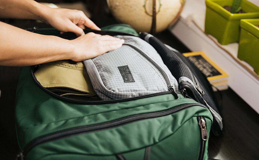 lifestyle visible^^Design Lab Edition Packing Cube Shoulder Bag being packed in an Aeronaut 45 travel bag.