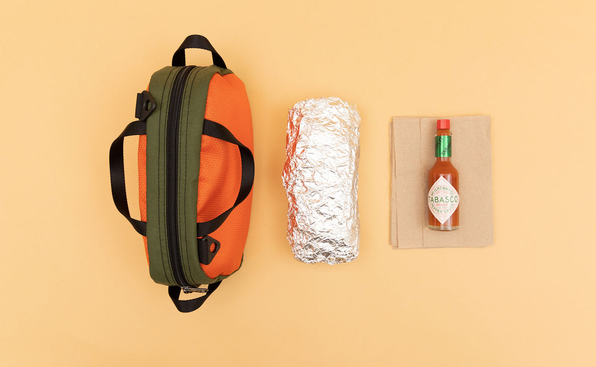detail visible^^ Texturized Orange Grab Bag next to a foil wrapped burrito and a bottle of Tabasco sauce.