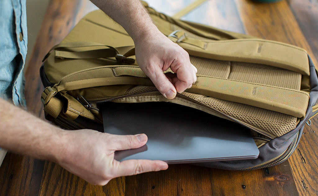 A person putting a laptop into the laptop compartment of the Guide's Edition Synik 30.
