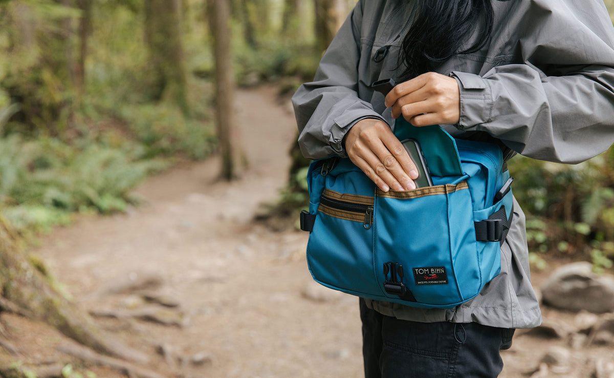 lifestyle visible^^Person accessing a phone from the front buckle pocket of the LGD while wearing it as a waist pack.