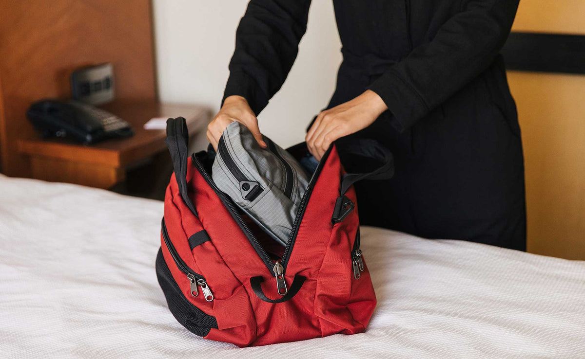 visible lifestyle^^Person pulling a Packing Cube Shoulder Bag out of the main compartment of the OSCA.