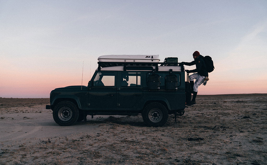 visible lifestyle^^A person carrying the Original Shadow Guide 31 while climbing up the roof ladder of a Jeep.