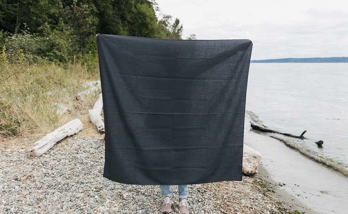 lifestyle visible^^ A person at the beach holding a Large Shepherd's Wool Utility Cloth in Matter Grey. 