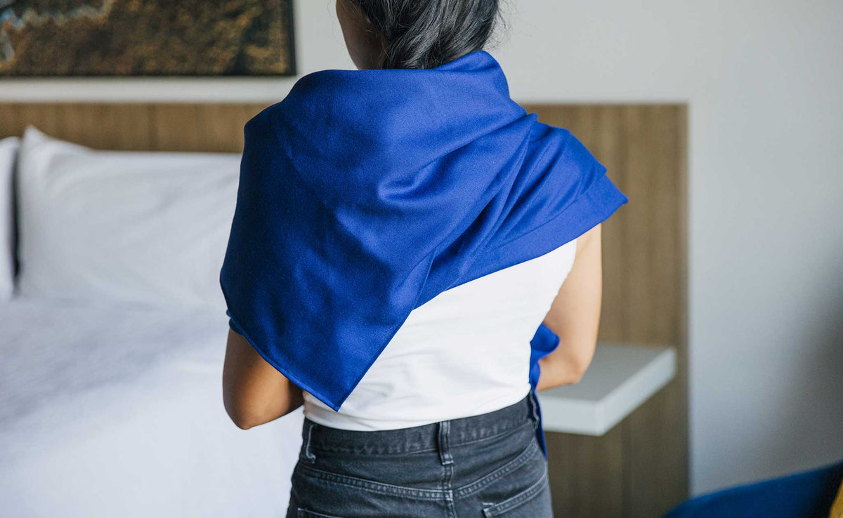 ifestyle visible^^ A Large Shepherd's Wool Utility Cloth in Neela Blue being worn as a scarf, artfully arranged at the back of the neck/shoulders.
