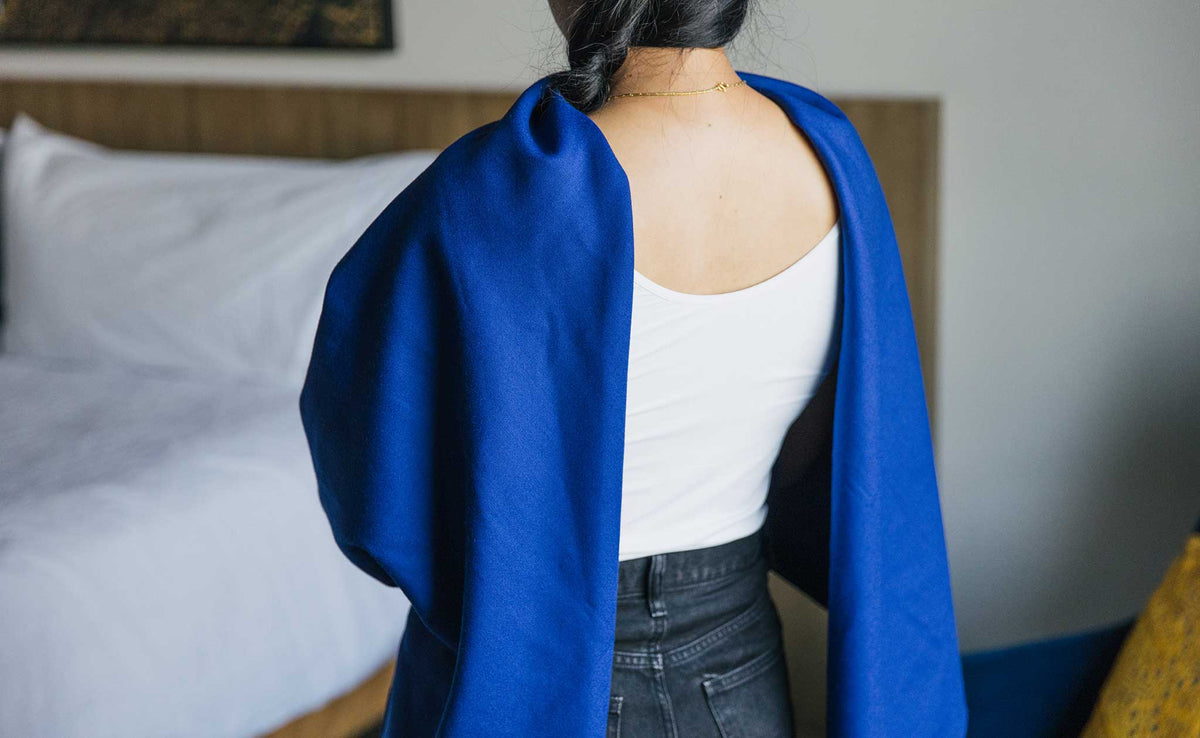 ifestyle visible^^ A Large Shepherd's Wool Utility Cloth in Neela Blue being worn as an open-back shawl.