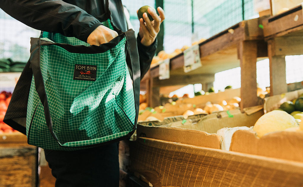 ^^Small Original Shop Bag in Sitka over the shoulder of a person shopping at an open air market.