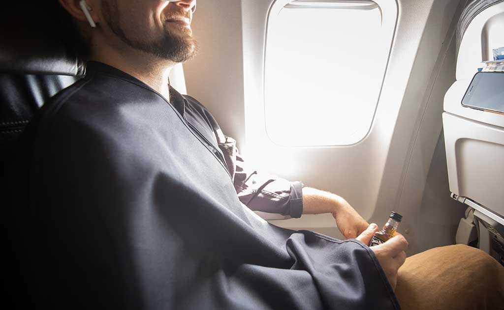 lifestyle visible^^A person covered with a Shepherd's Wool Utility Cloth on a flight.