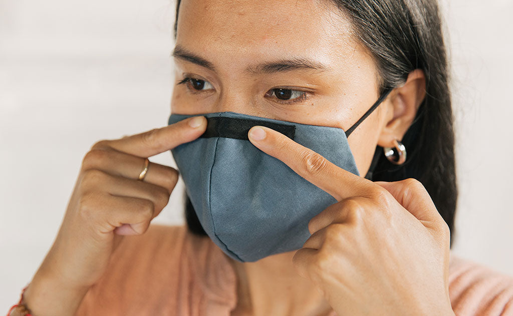 visible variant ME00010-LO^^Person wearing the V5 Mask, Pacific Blue, size Small/Medium. Adjusting the conforming nose piece.